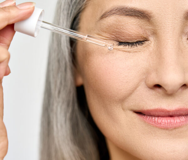 Closeup cut portrait of mature senior Asian woman with pipette serum essence.