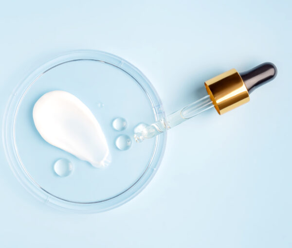 smear of cream stroke and round transparent drop of gel serum in a petri dish on a blue background. Concept laboratory tests and research, making and testing cosmetic